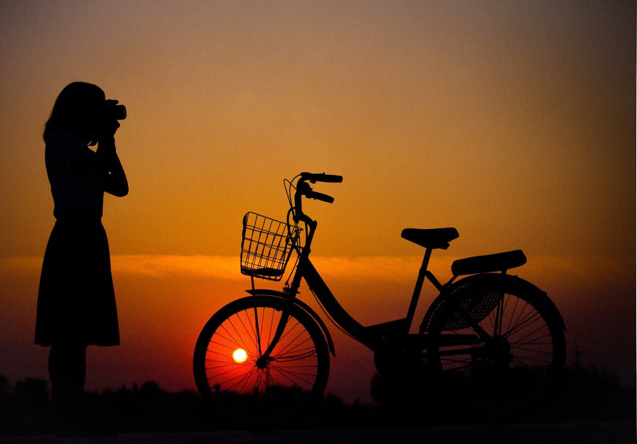 Silhouette of Woman Using Camera in Front of City Bicycle